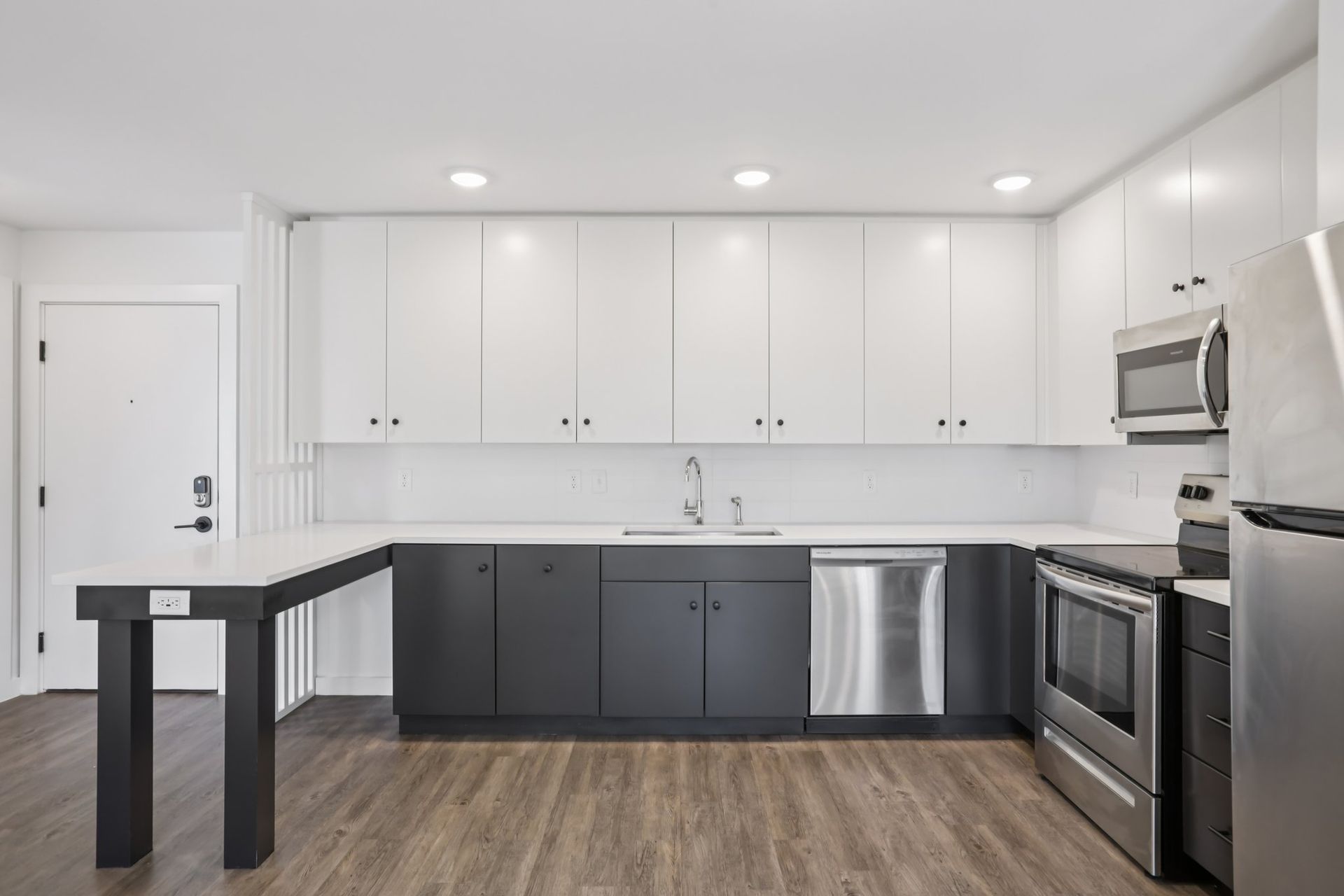 A modern kitchen with two-toned cabinetry, white uppers, charcoal lowers, stainless appliances, and a peninsula counter.