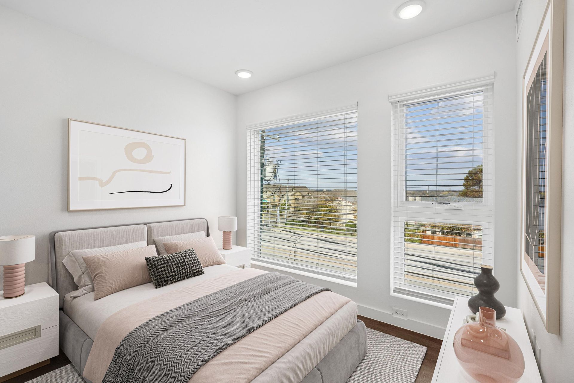 A modern, minimalist bedroom with a bed, two nightstands, and two large windows with a view of an outdoor landscape.