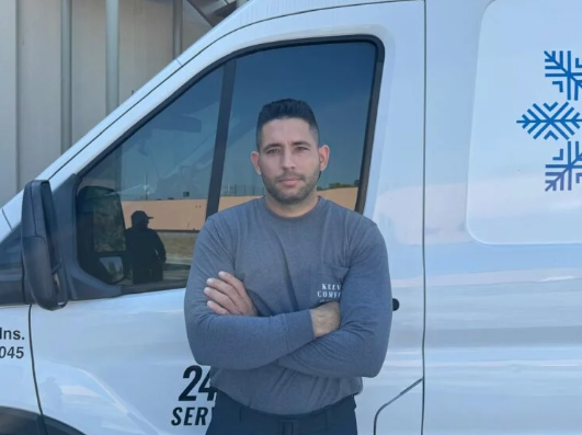 Man standing in front of a white van with crossed arms; snowflakes and