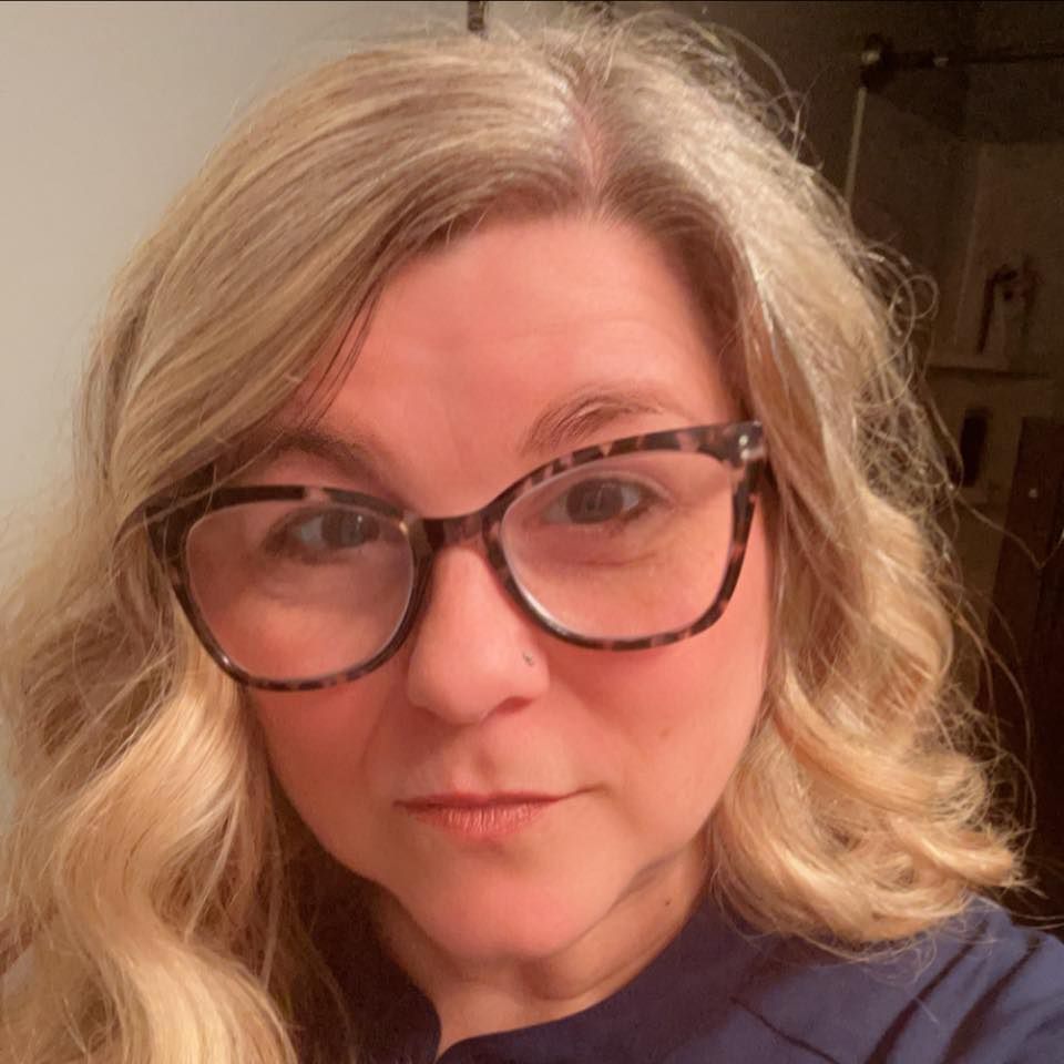 Young person with curly brown hair, leaning on a yellow television; they have a pensive expression.