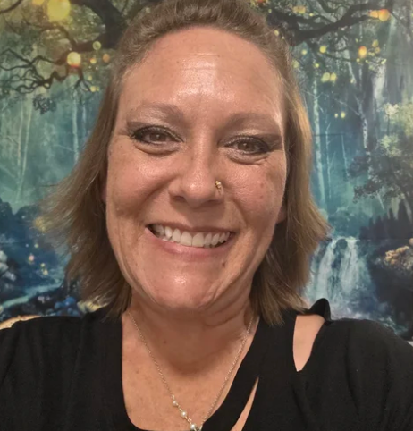Young person with curly brown hair, leaning on a yellow television; they have a pensive expression.