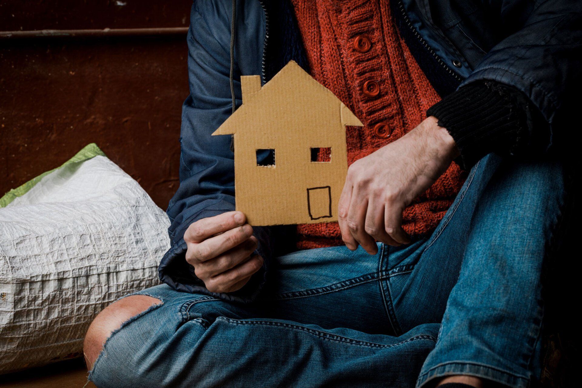 homeless man holding a house cardboard cut-out