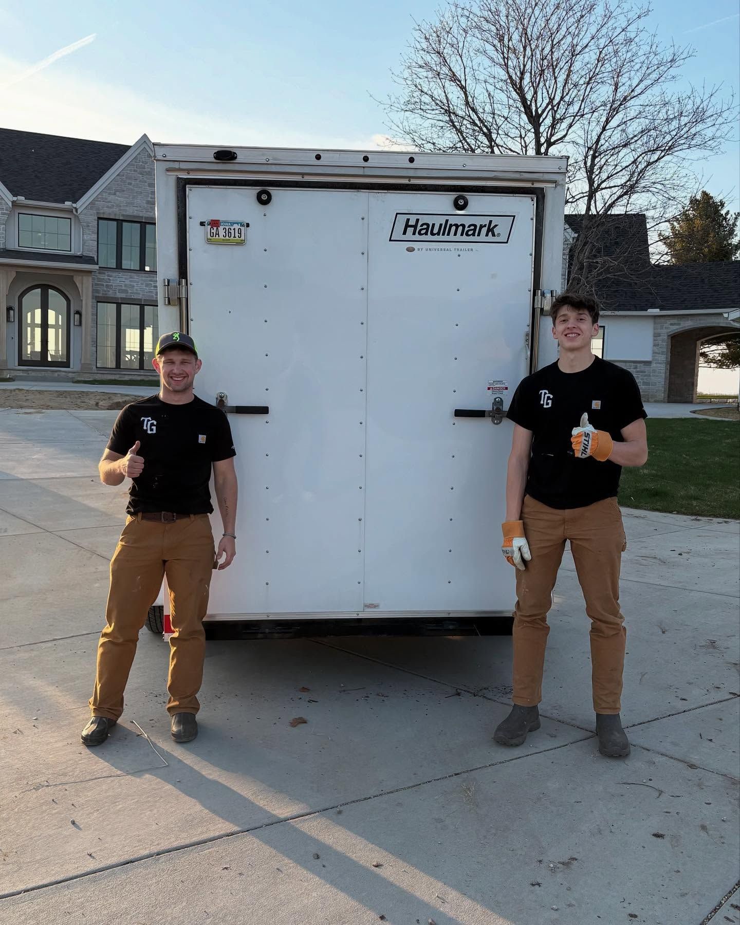 Two men are standing in front of a haumann trailer