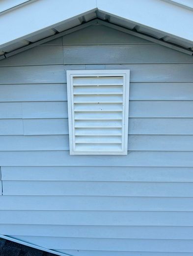 A white shutter is hanging on the side of a house.