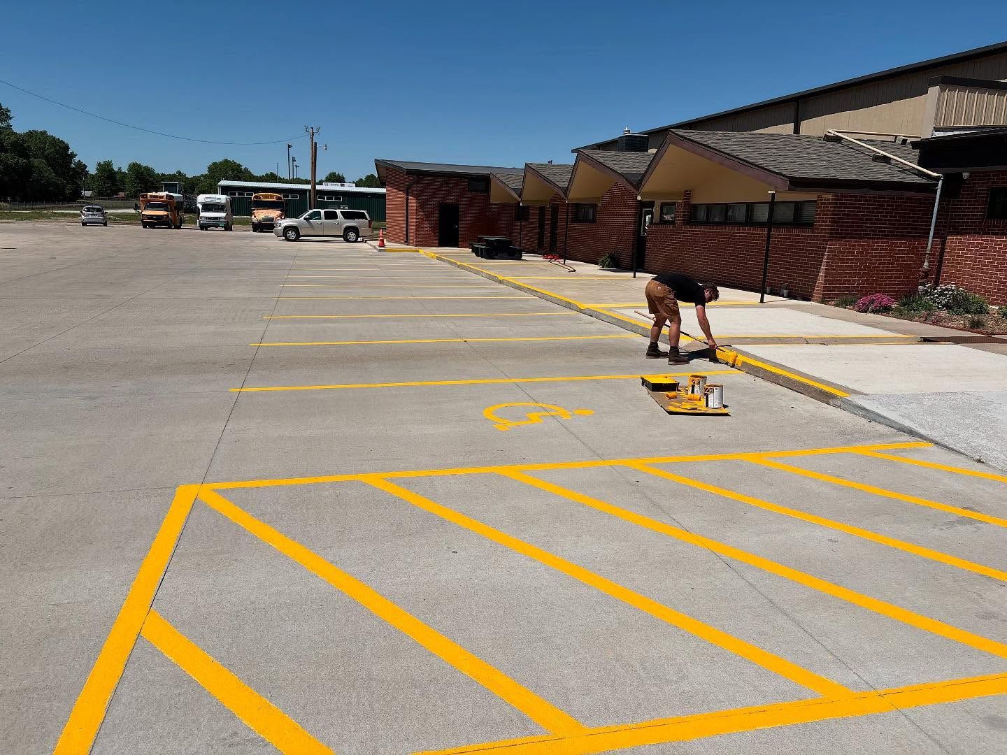 A man is painting a handicapped parking spot in a parking lot