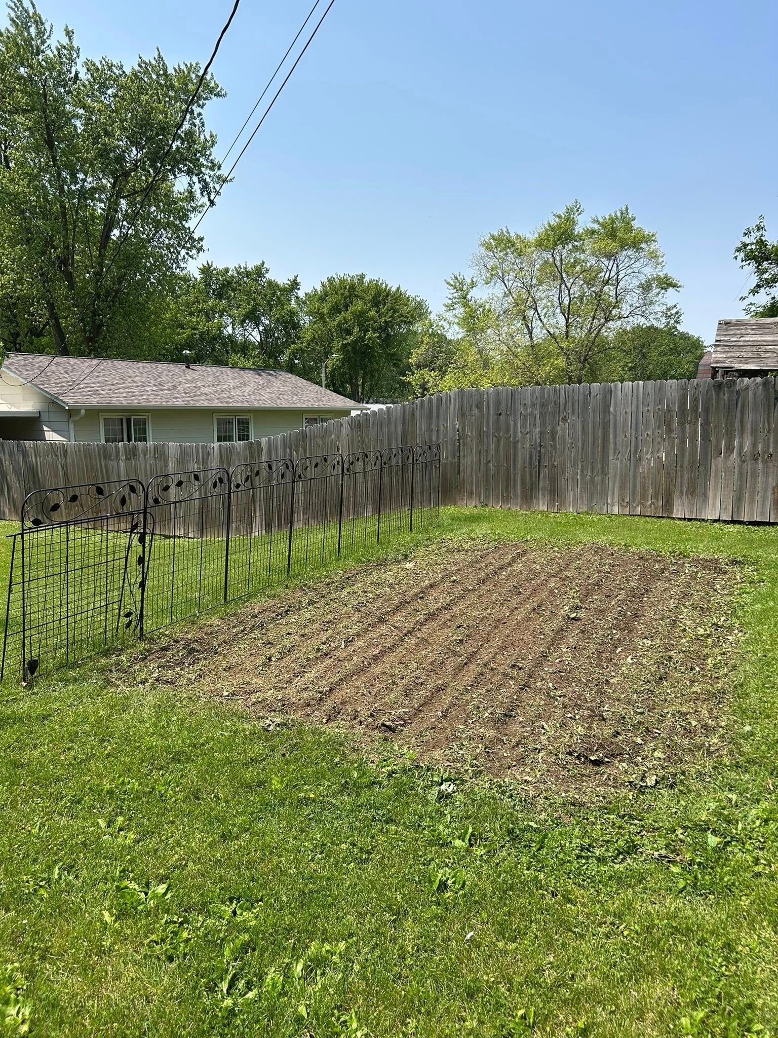 A wooden fence surrounds a lush green yard.