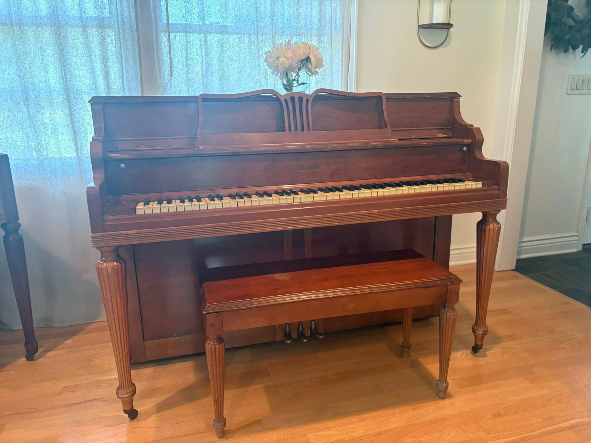 A piano is sitting in a living room next to a window.
