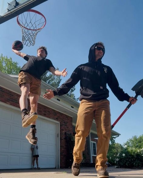 Two men are playing basketball in front of a garage door.