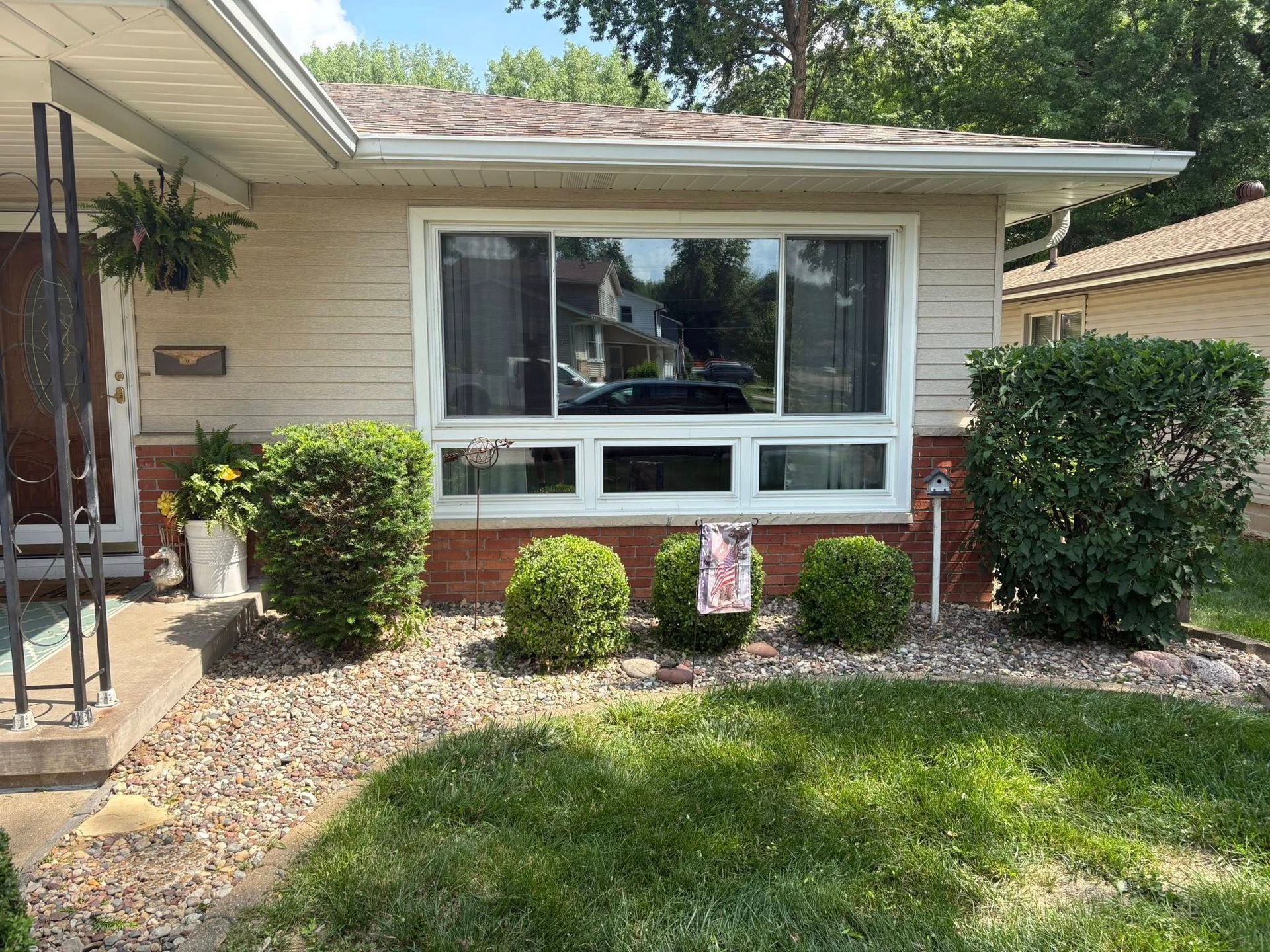 A house with a large window and a lawn in front of it.