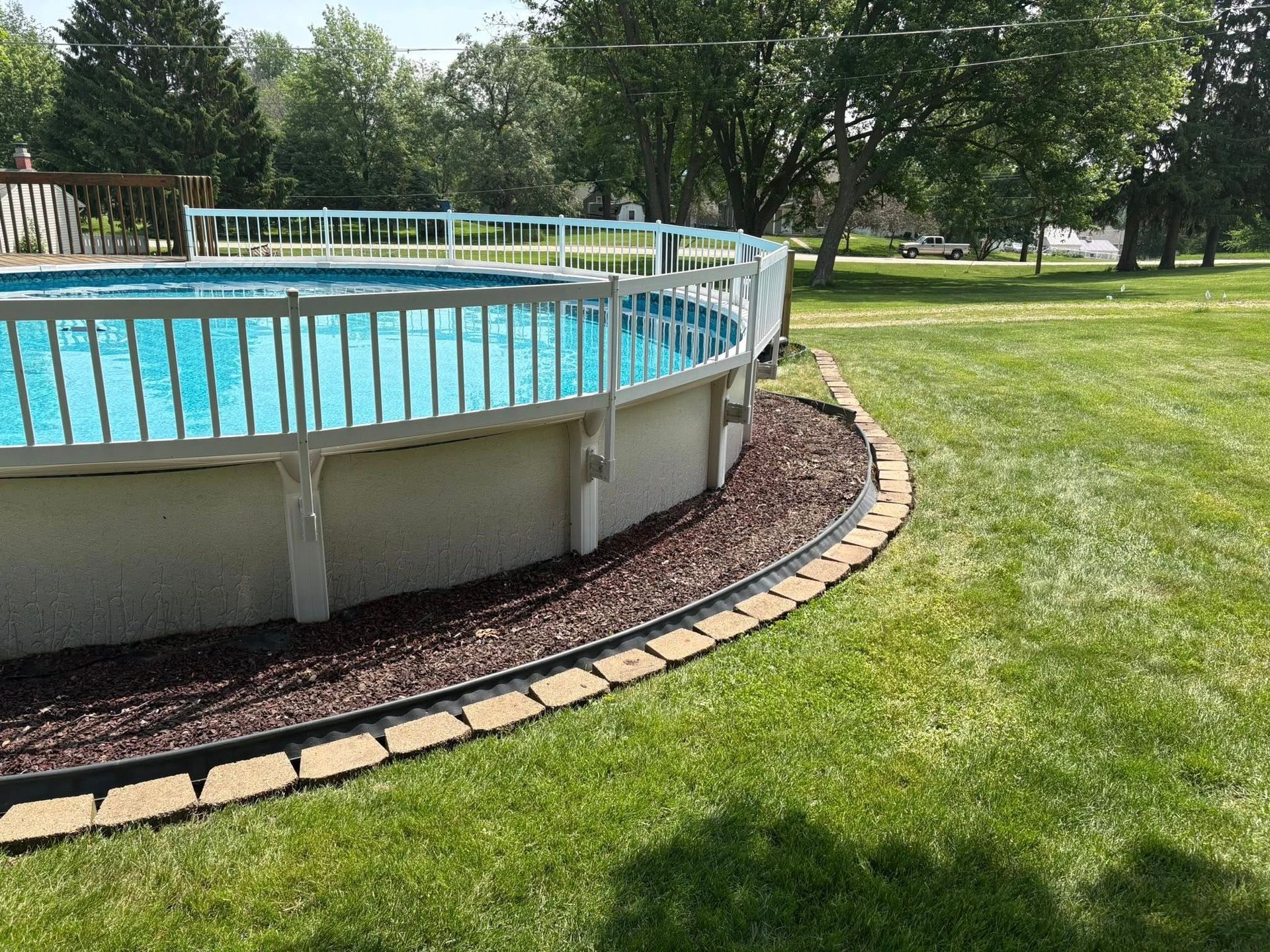 A large swimming pool is sitting in the middle of a lush green field.