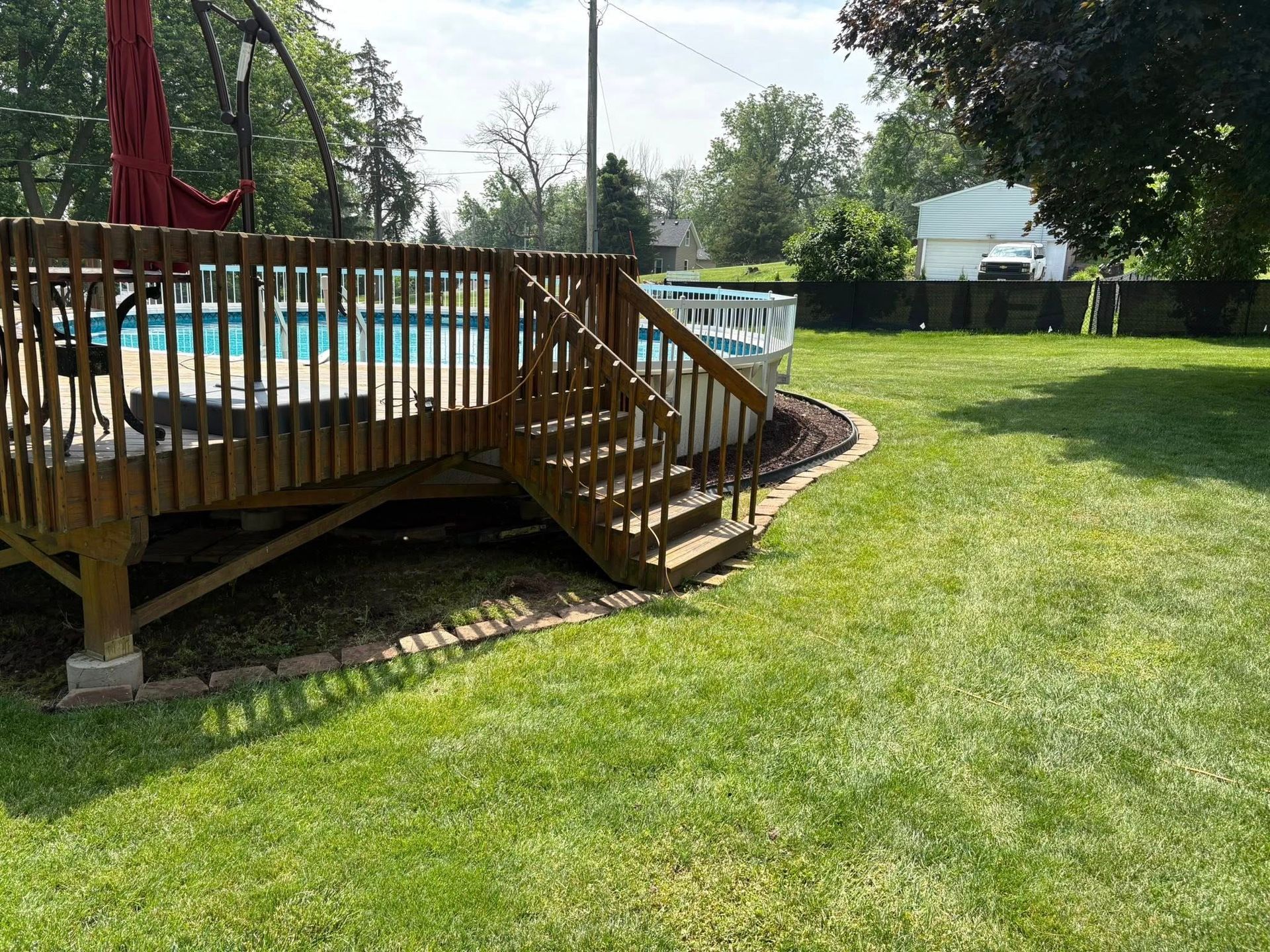 A wooden deck with stairs leading up to a swimming pool.