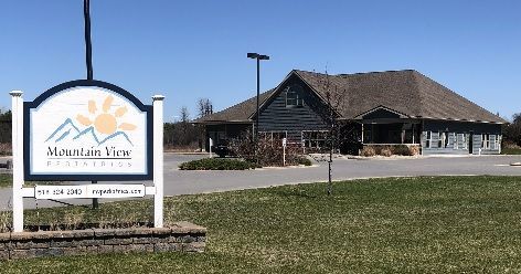 Sign for Mountain View Business, a light blue building with a brown roof and a blue sky.