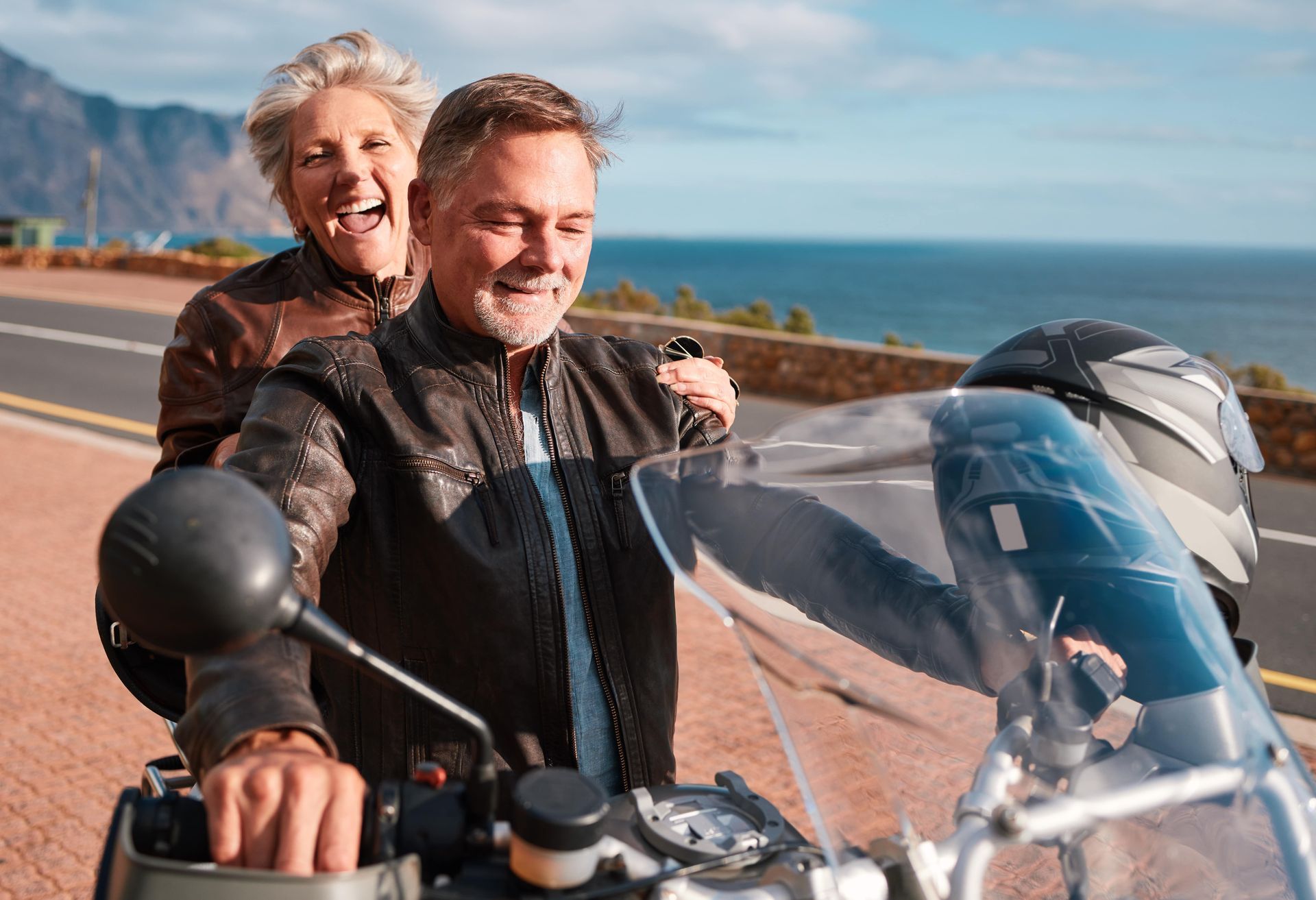 A man and a woman are riding a motorcycle on a road.