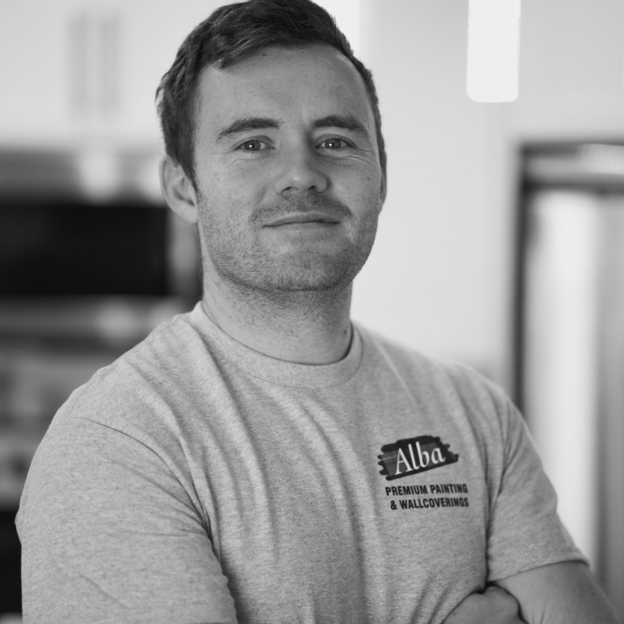 A man wearing an alba t-shirt with his arms crossed