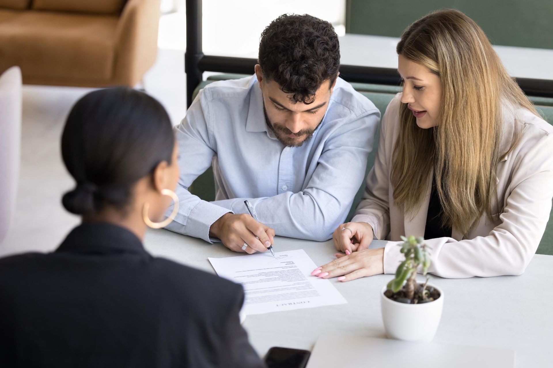 Woman in business attire with couple reviewing documents at a table.