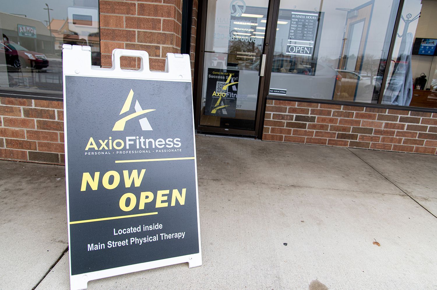 An A-frame sign outside Axlo Fitness reads