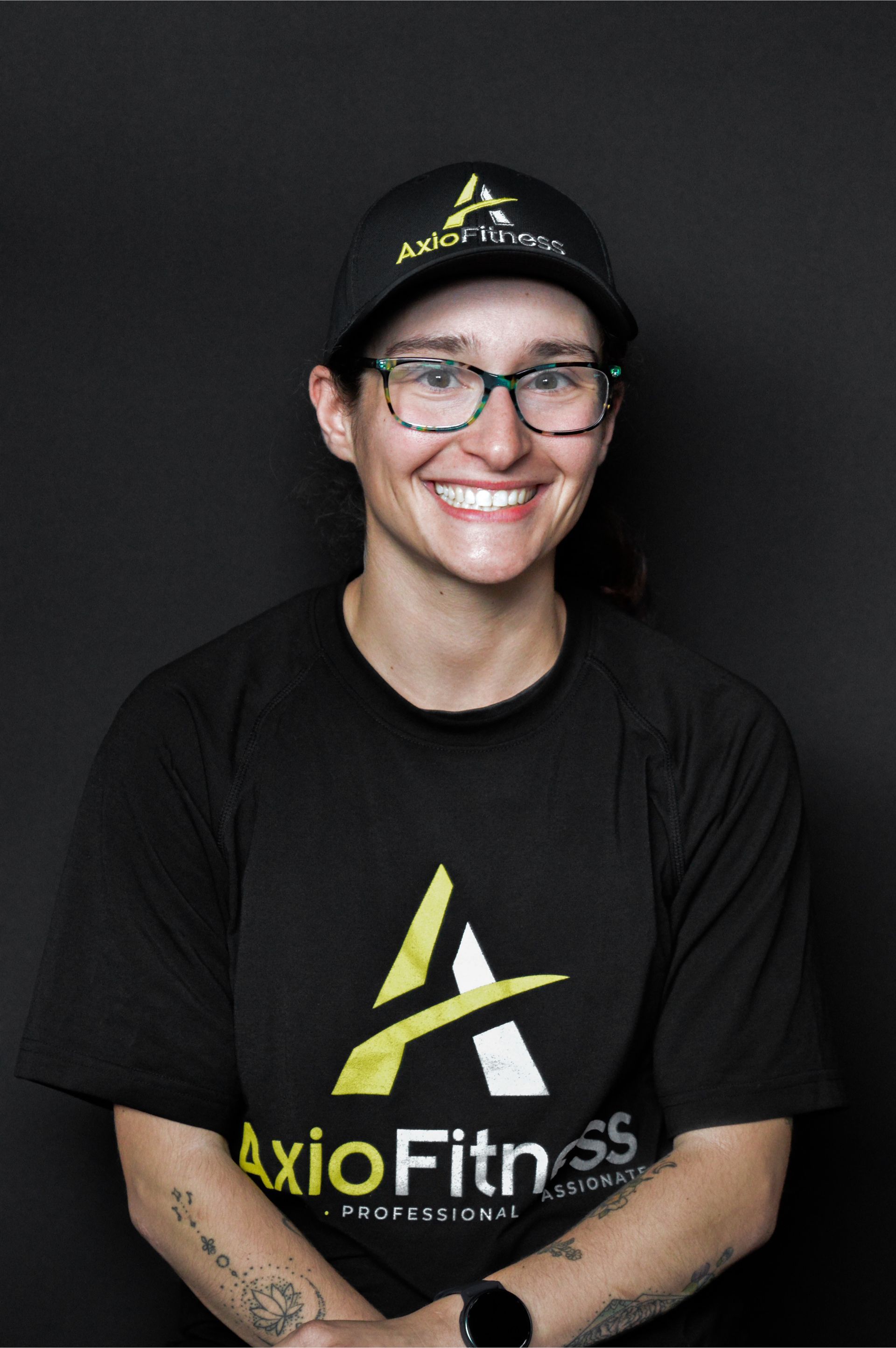 Man in a black AxioFitness t-shirt, seated and smiling, against a black backdrop.