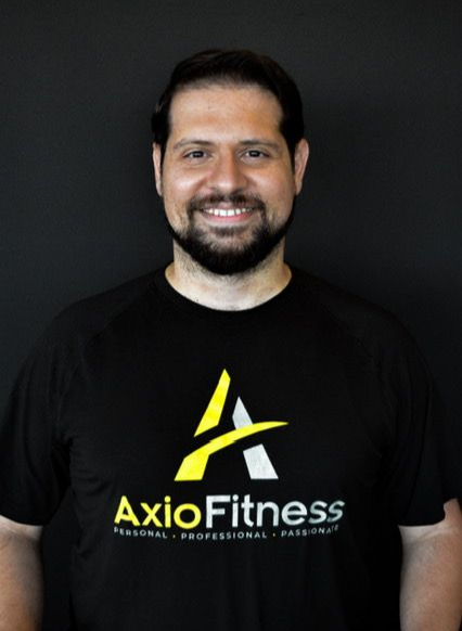Man wearing a black AxioFitness t-shirt, smiling, with a dark background.