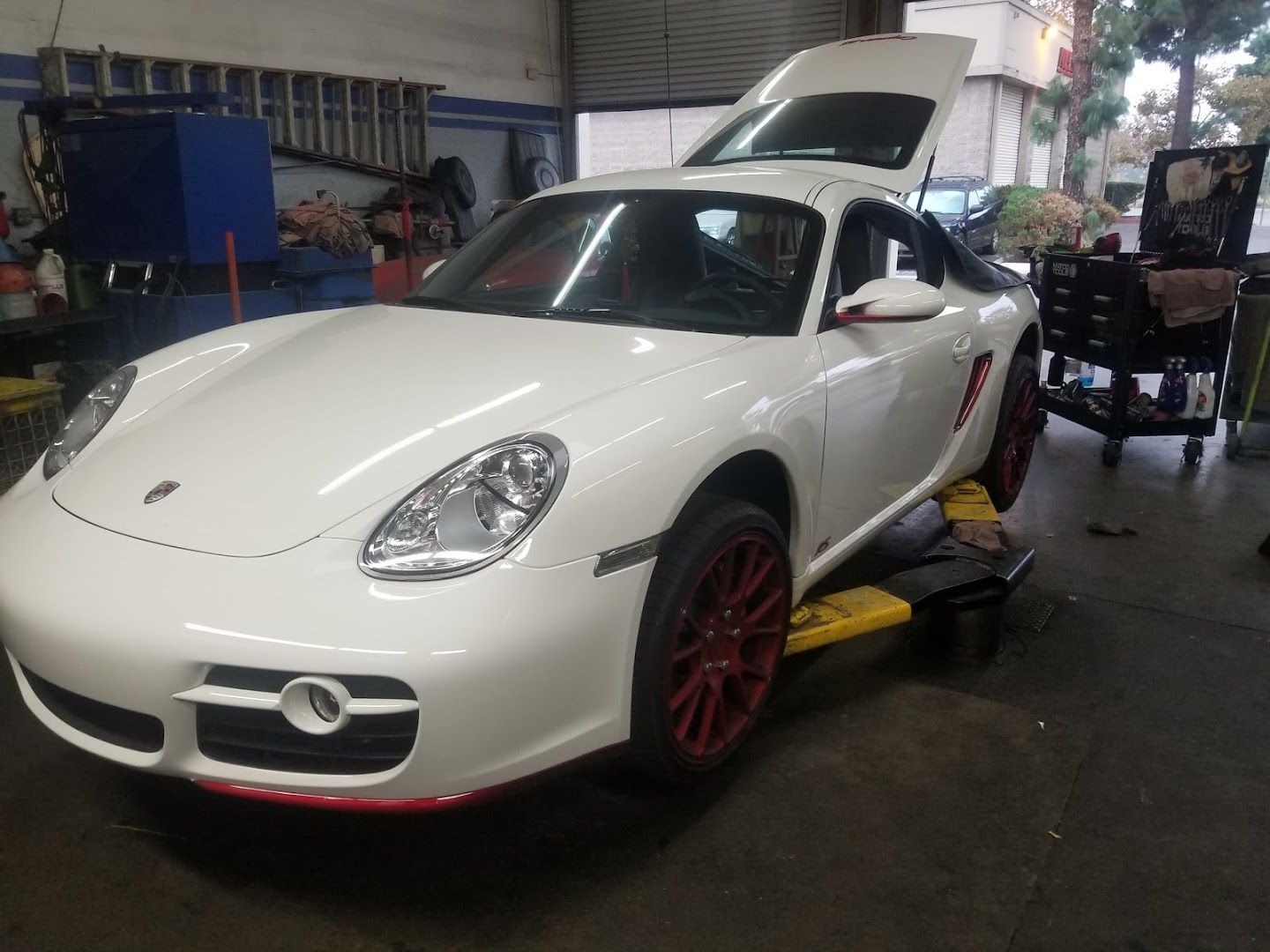 A white porsche is sitting on a lift in a garage.