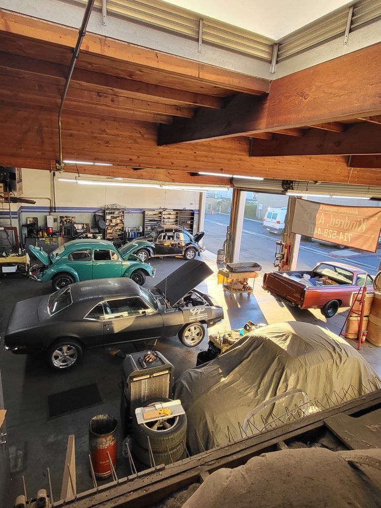 A bunch of cars are parked in a garage with their hoods open.