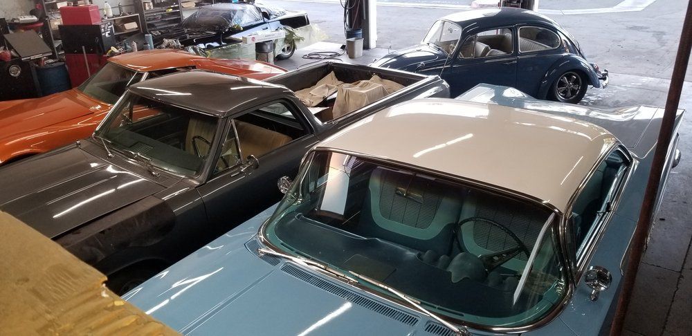 A row of old cars are parked in a garage.