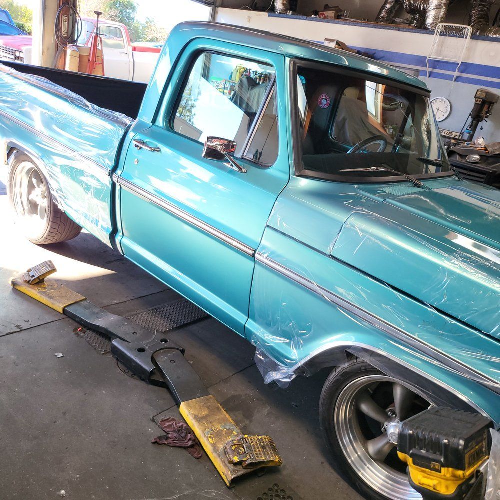 A blue truck is sitting on a lift in a garage.