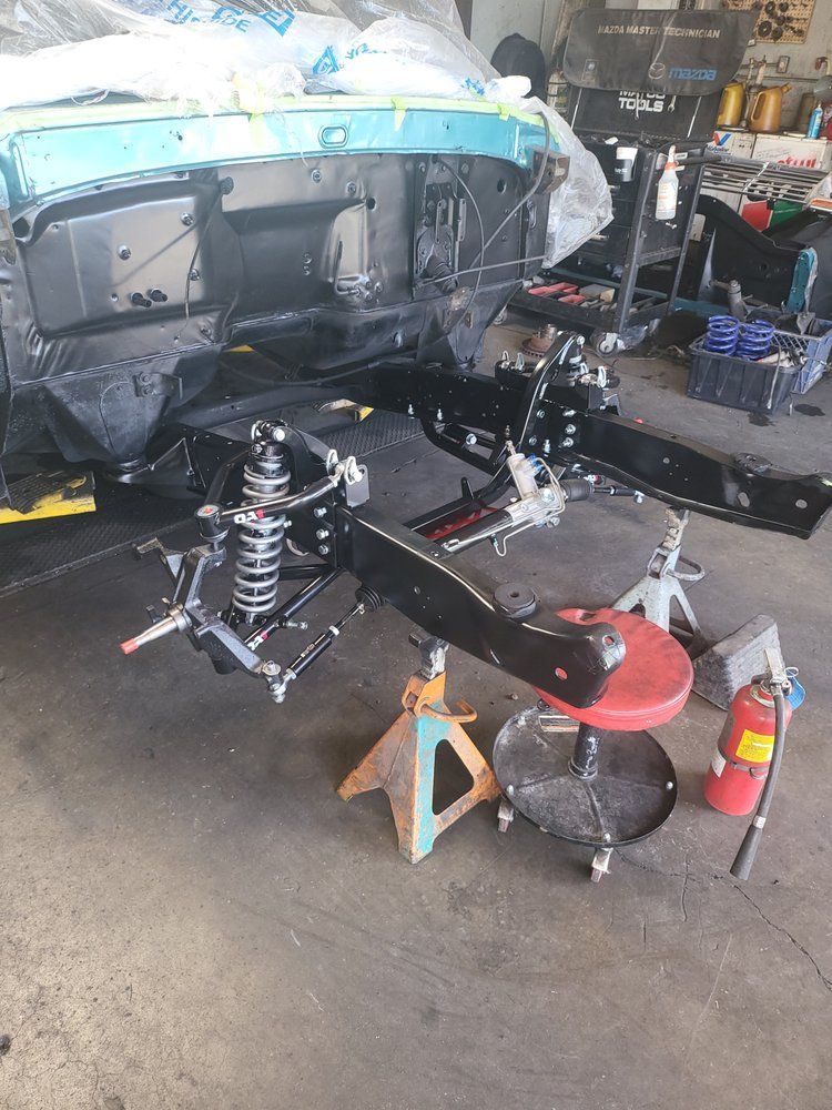 A car is being built in a garage with a fire extinguisher on the floor.