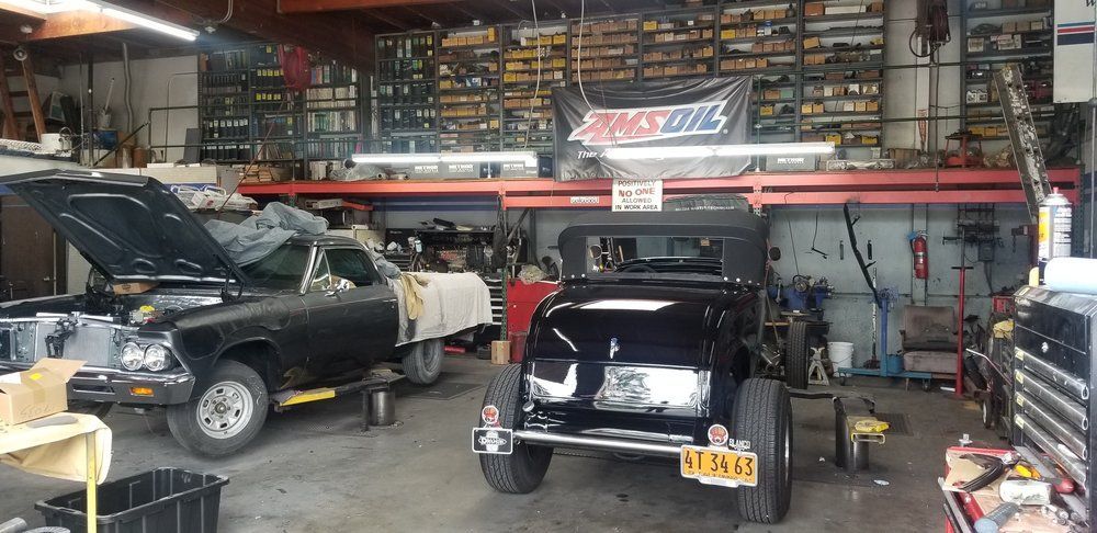 A jeep is being worked on in a garage with a sign that says amsoil