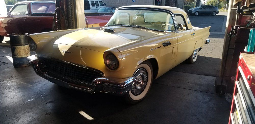 A gold car with white tires is parked in a garage