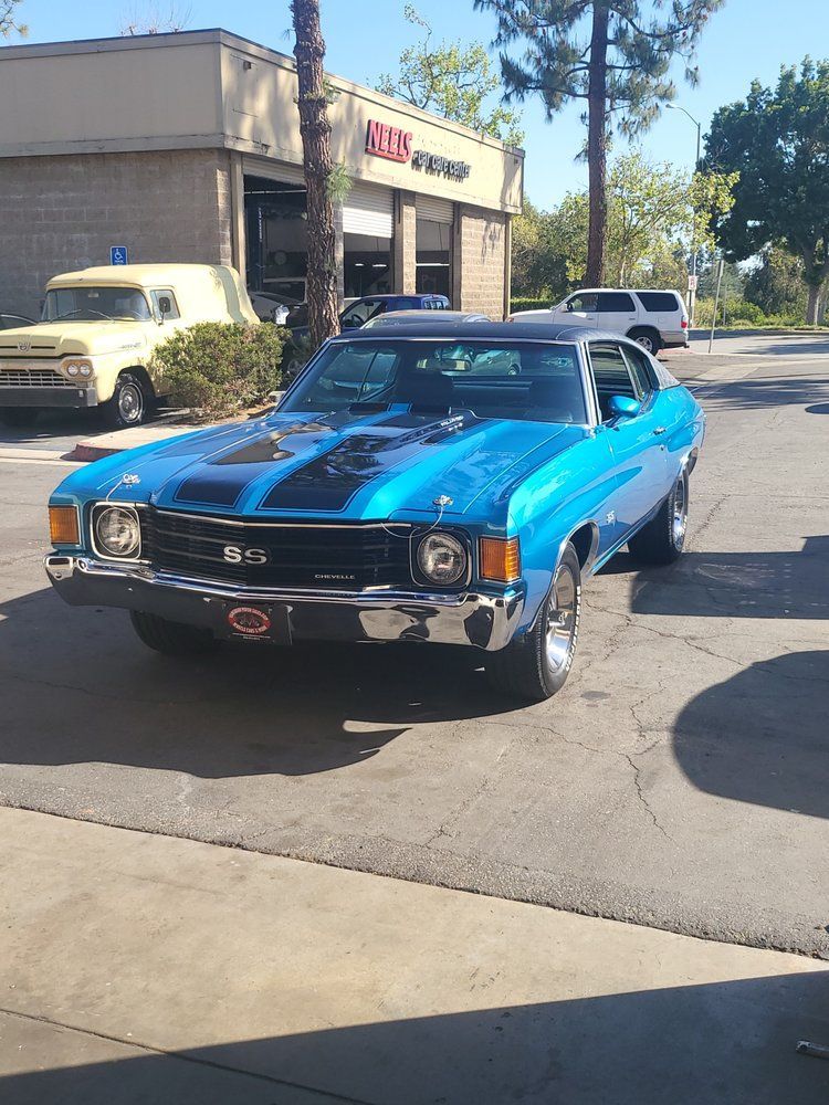 A blue car is parked in front of an auto repair shop