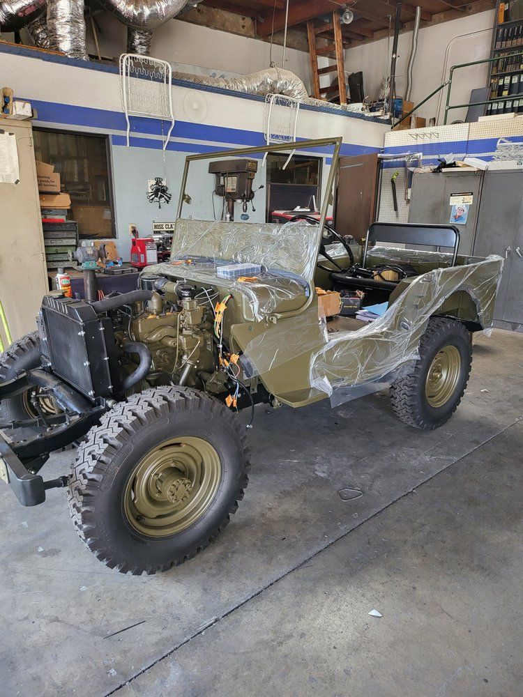 A green jeep is parked in a garage.