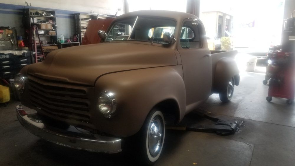 An old brown truck is parked in a garage.