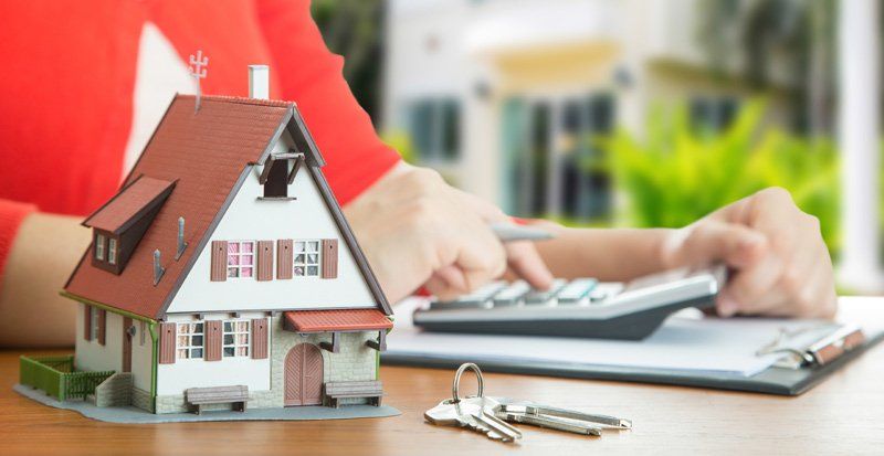Woman Using Calculator and Miniature House — Norfolk, VA — Temple Mortgage LLC