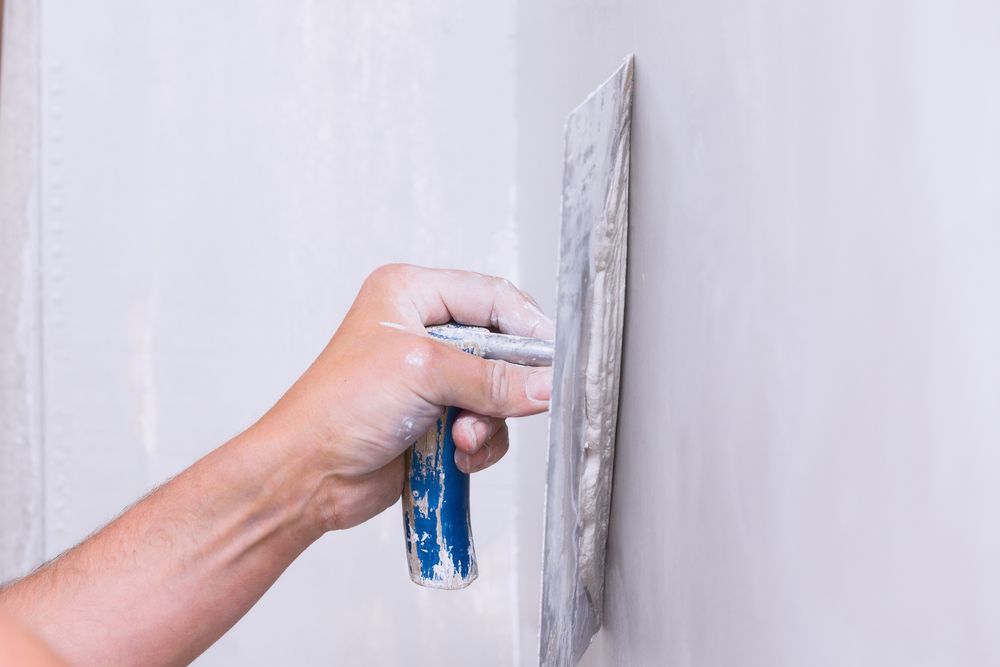 A Person Is Plastering a Wall with A Trowel — Completely Plastered North Coast in Mullumbimby, NSW