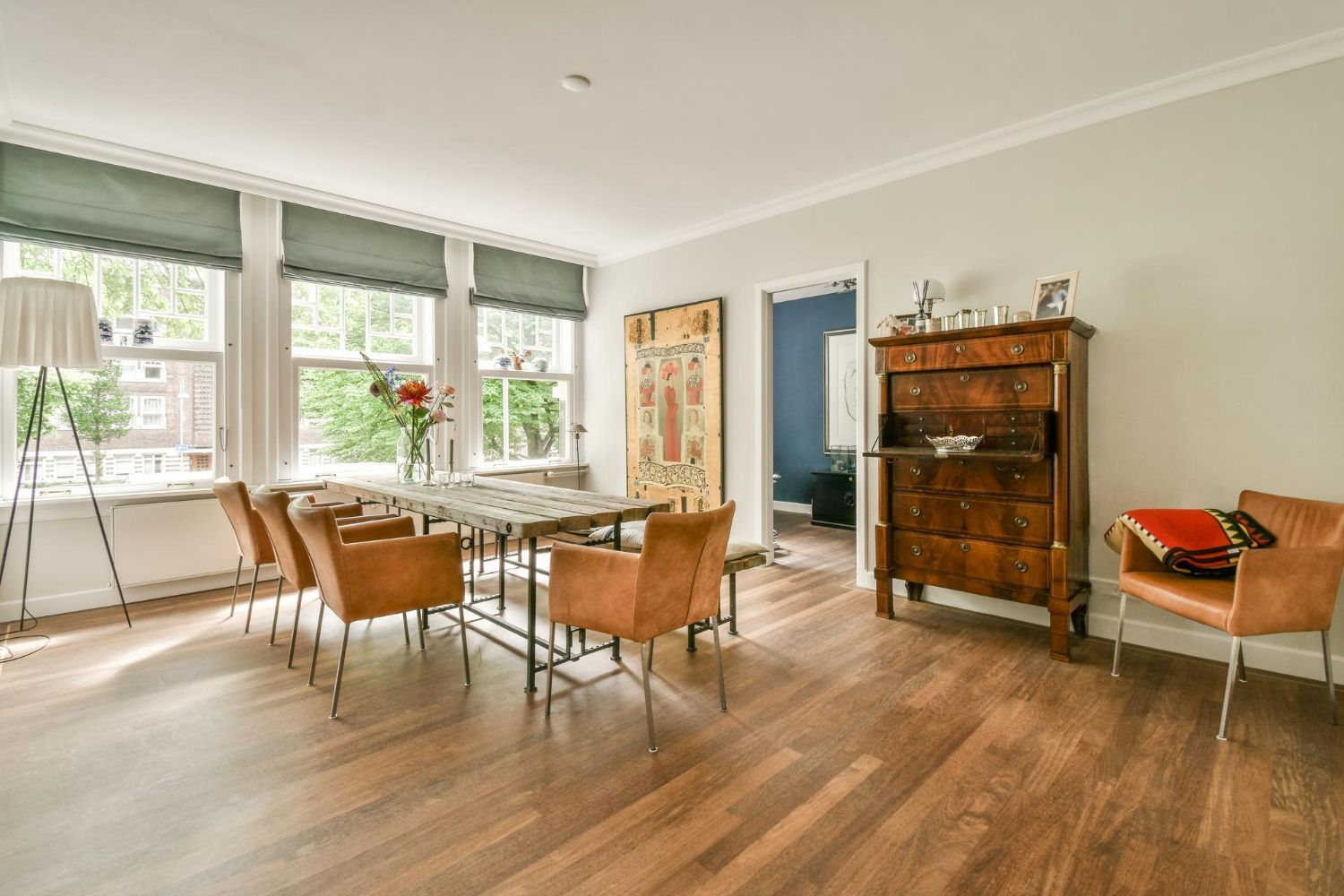 Dining room with wooden floor, table, chairs, and antique dresser.