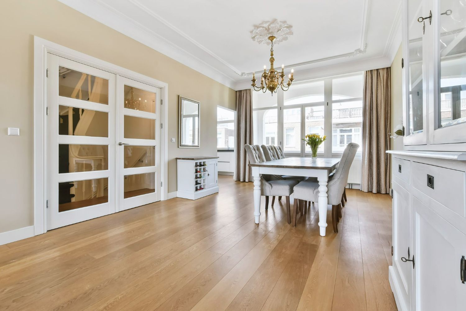 Dining room with hardwood floor, white furniture, and a chandelier.