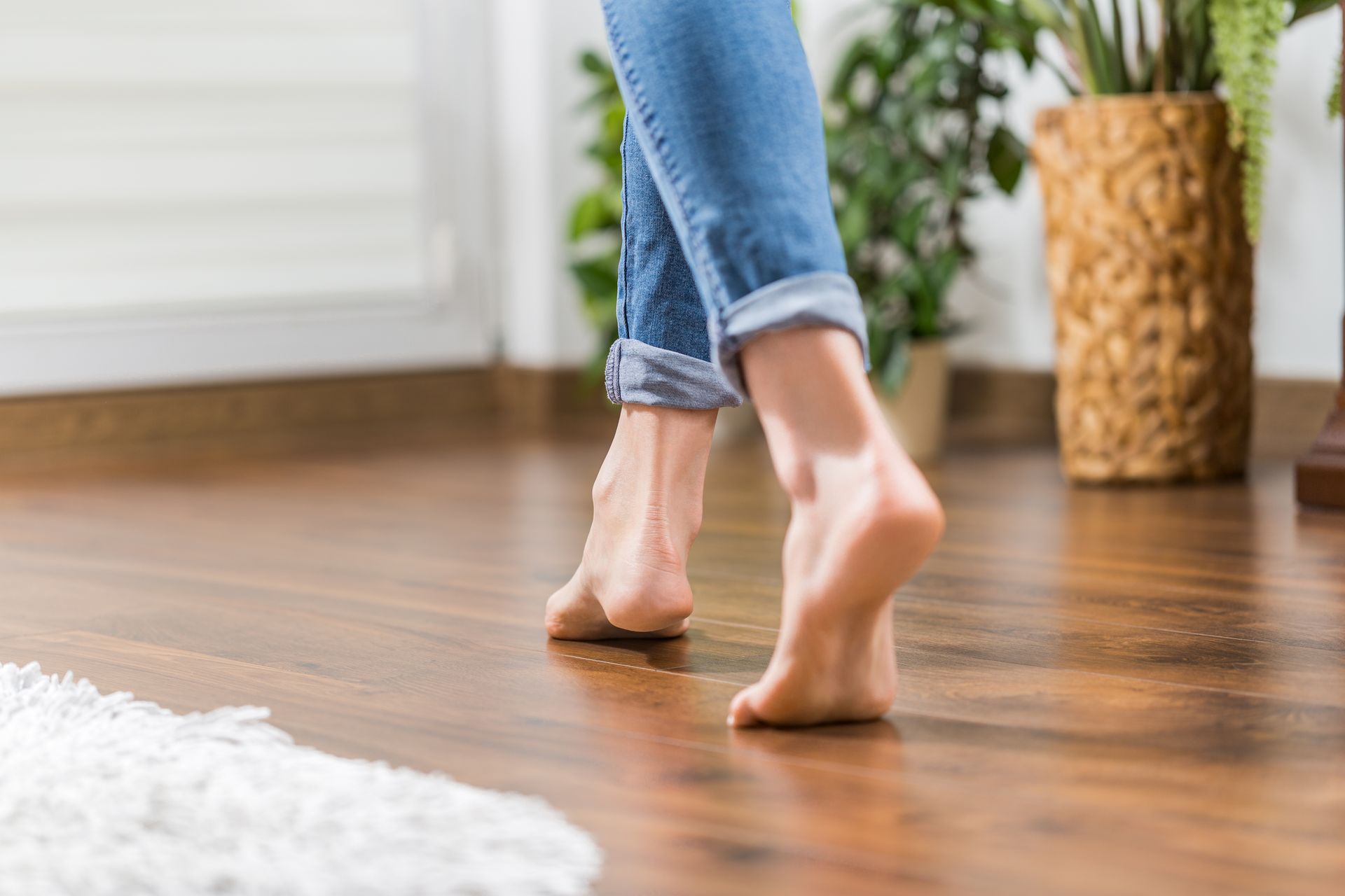 A woman is walking barefoot on a wooden floor.