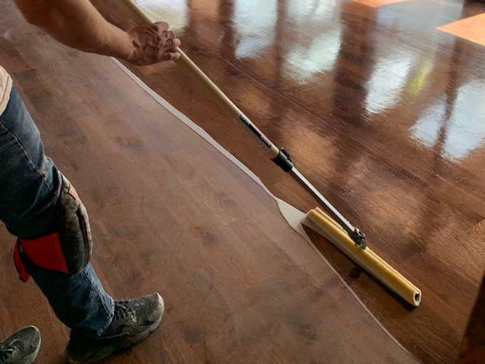 Worker man staining wood floors