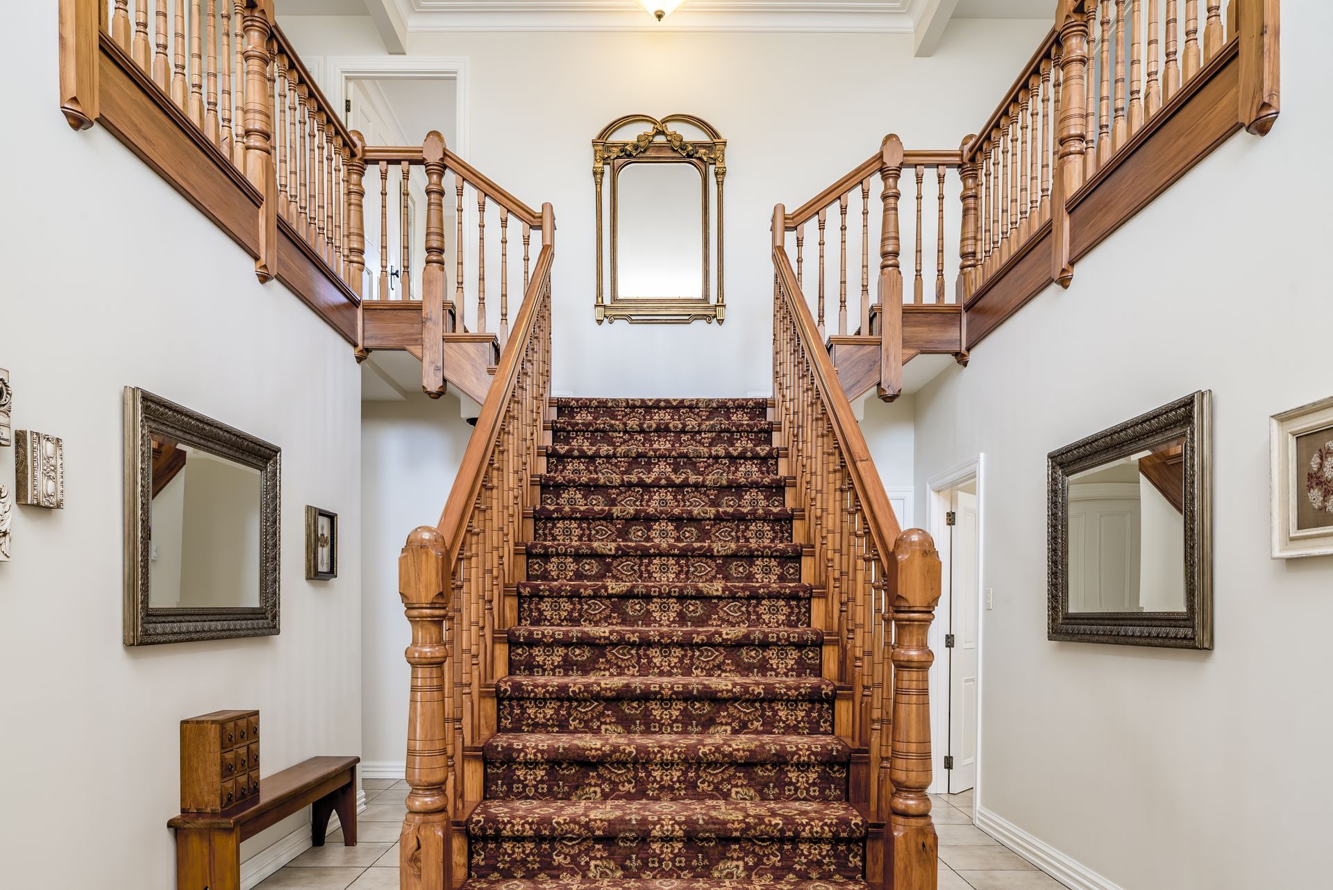 A large wooden staircase with a carpeted staircase in a hallway.