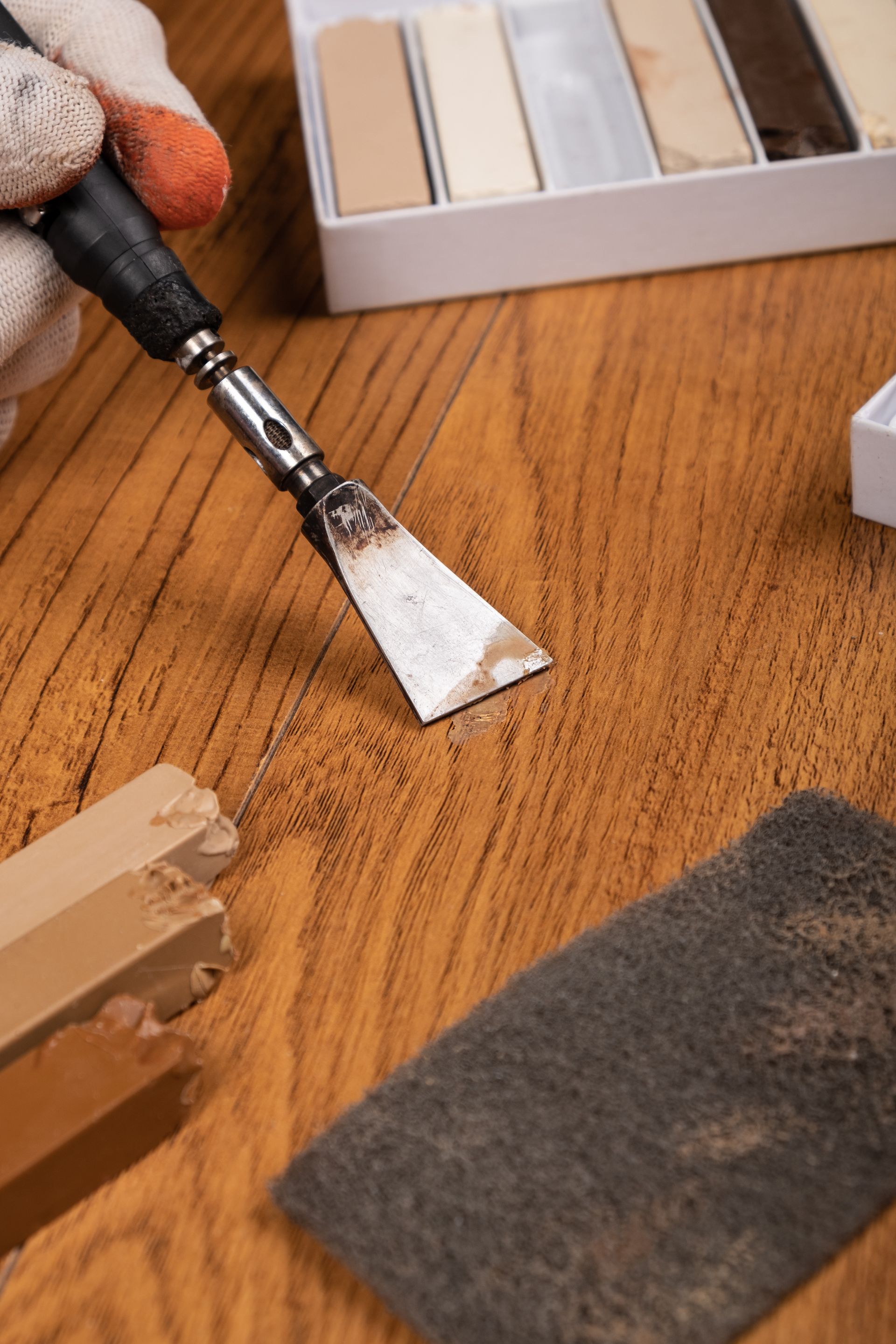 A person is scraping a piece of wood with a spatula.