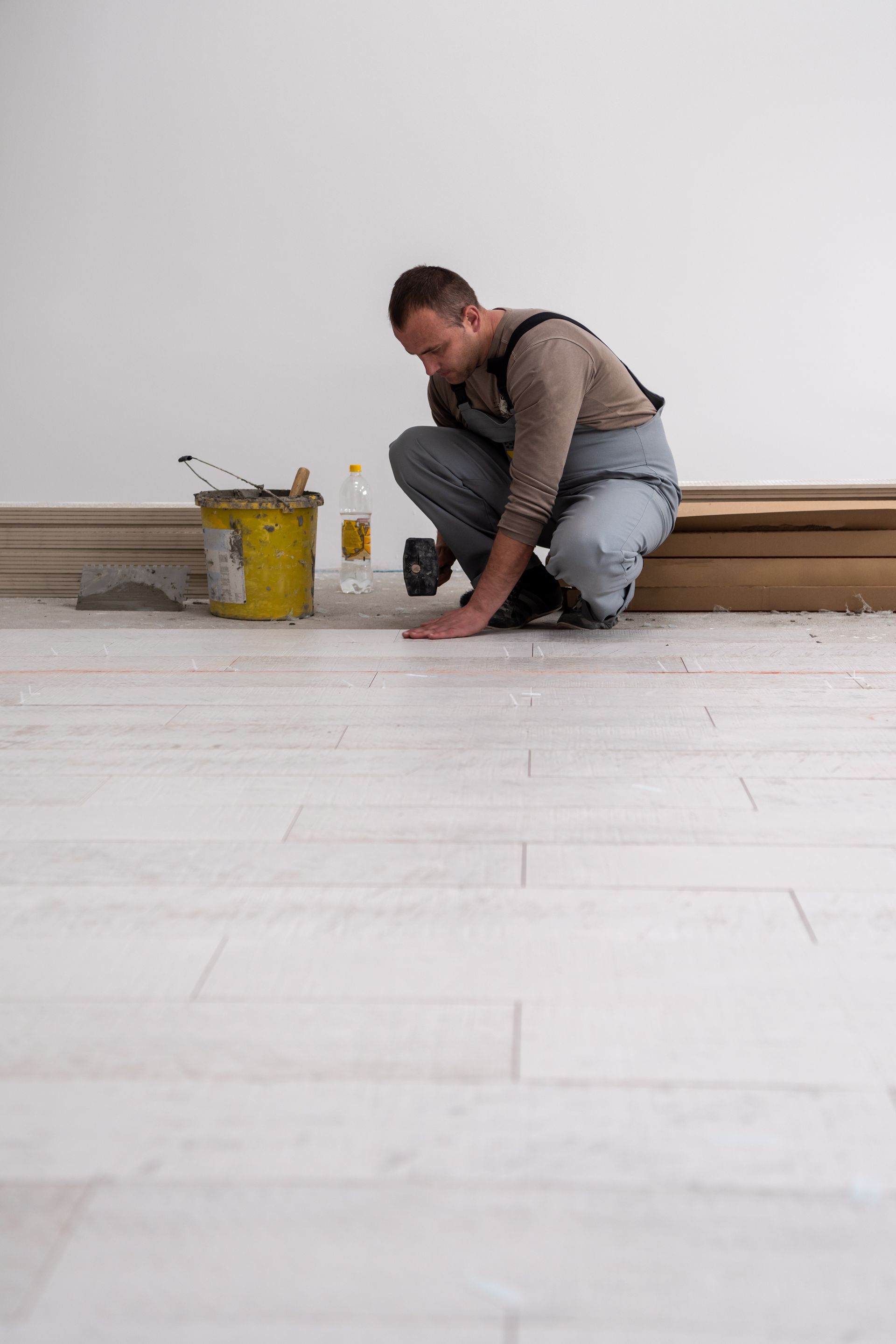 A man is kneeling down on a tiled floor.