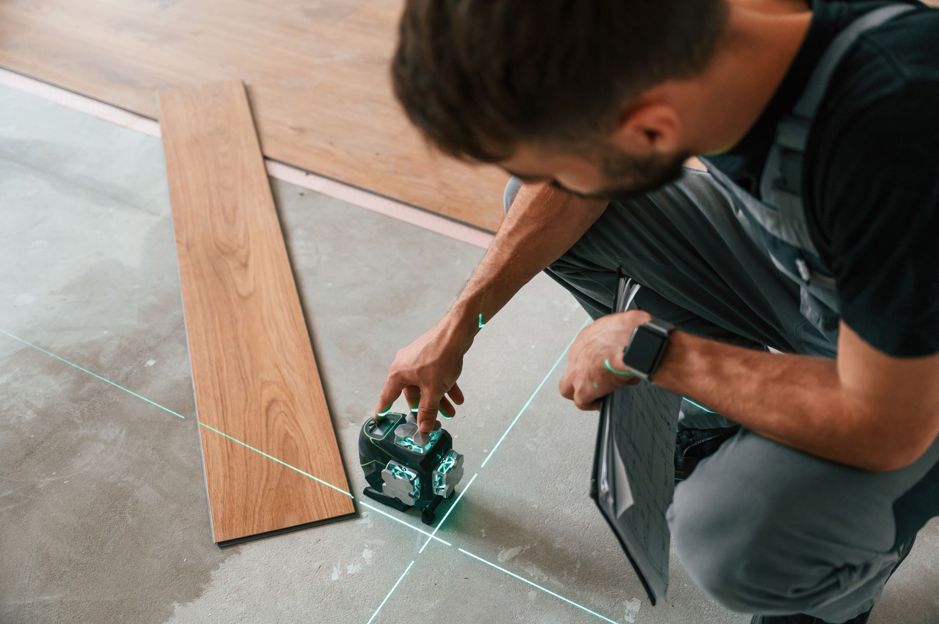 A man is measuring a piece of wood with a laser.