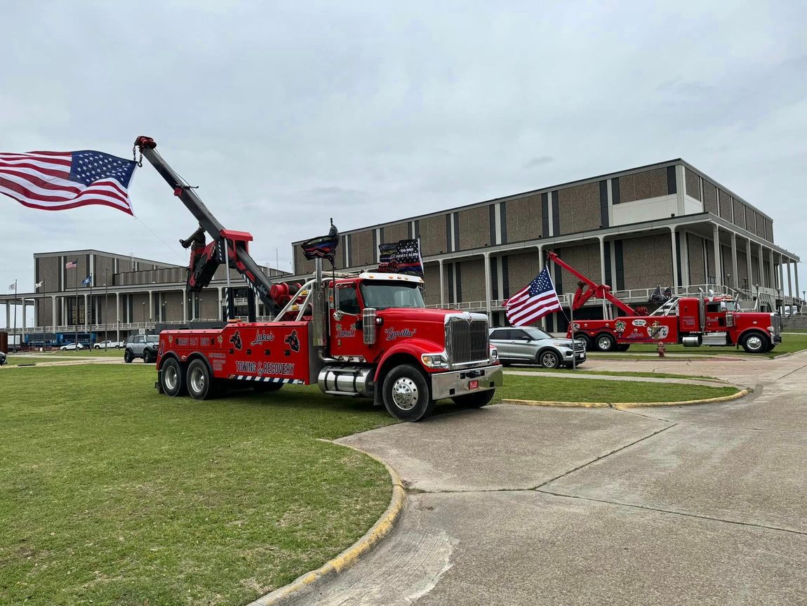 A tow truck is parked in front of a building with an american flag.