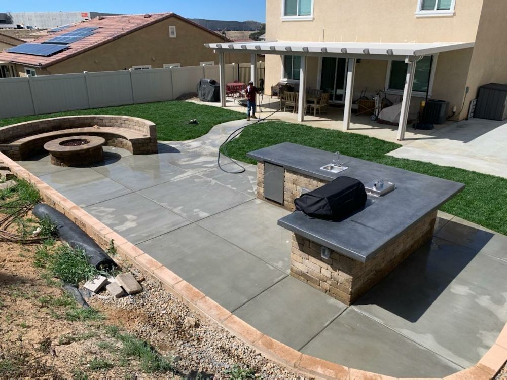 Yard with firepit and block island with grill, sink, and fridge.