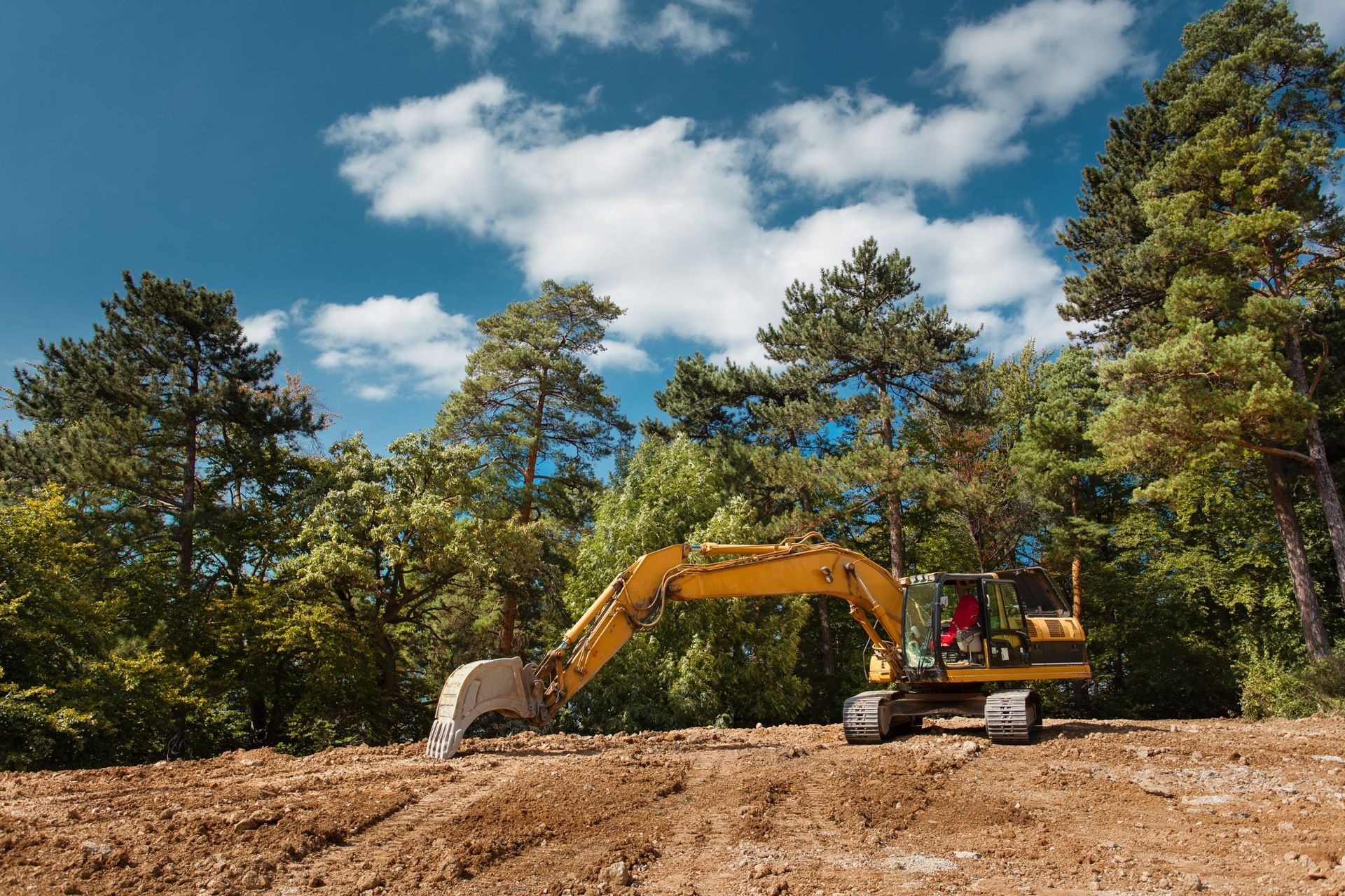 A yellow excavator is moving gravel on a construction site.