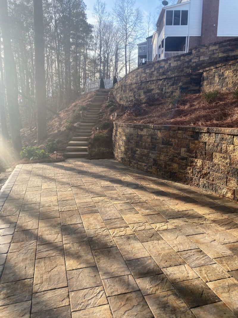 a stone patio with stairs leading up to a house on a hill .