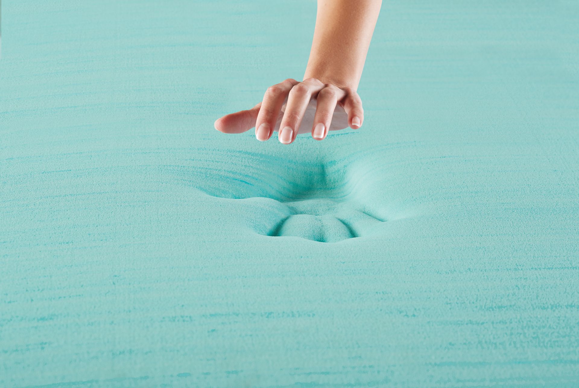La mano de una persona alcanza un colchón de espuma azul.