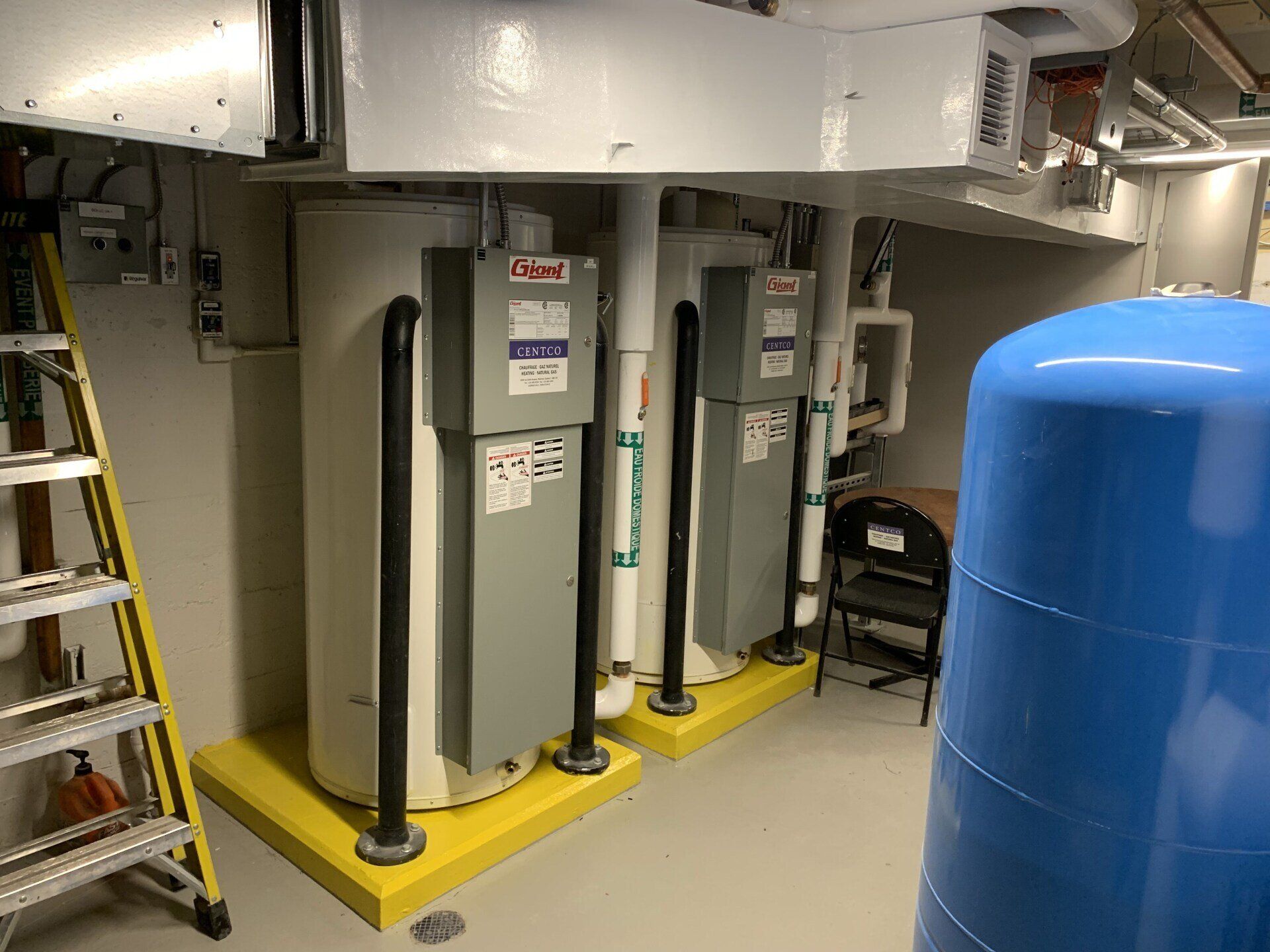 Une pièce avec deux chauffe-eau et un réservoir bleu.