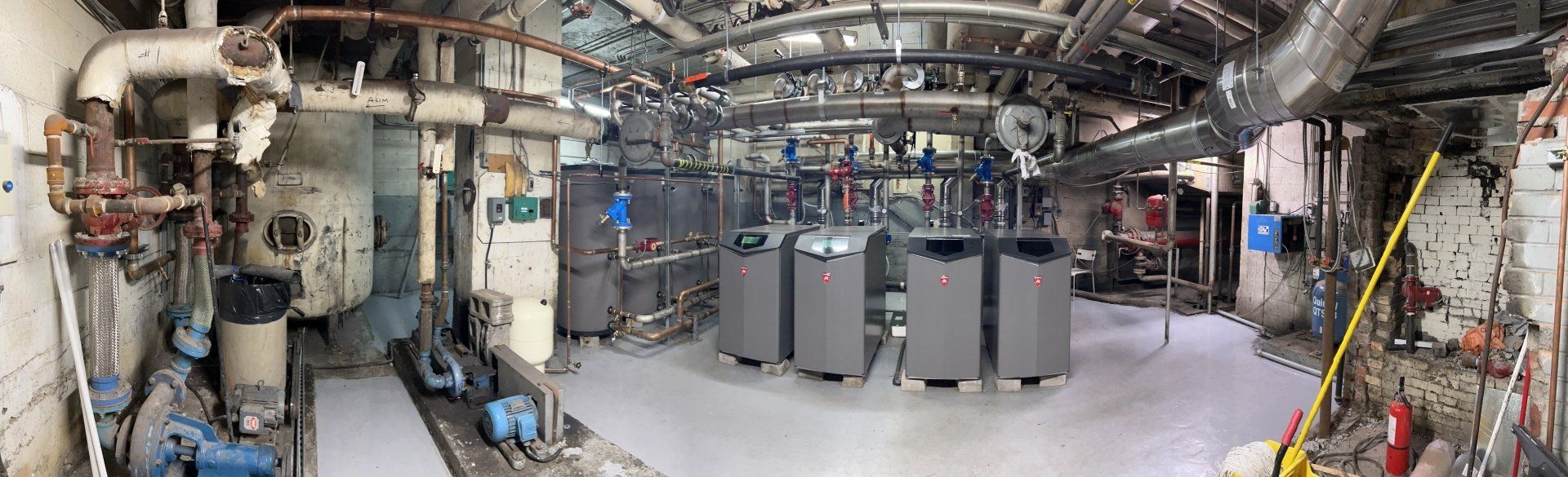 Une grande pièce avec beaucoup de tuyaux et de machines à l'intérieur.