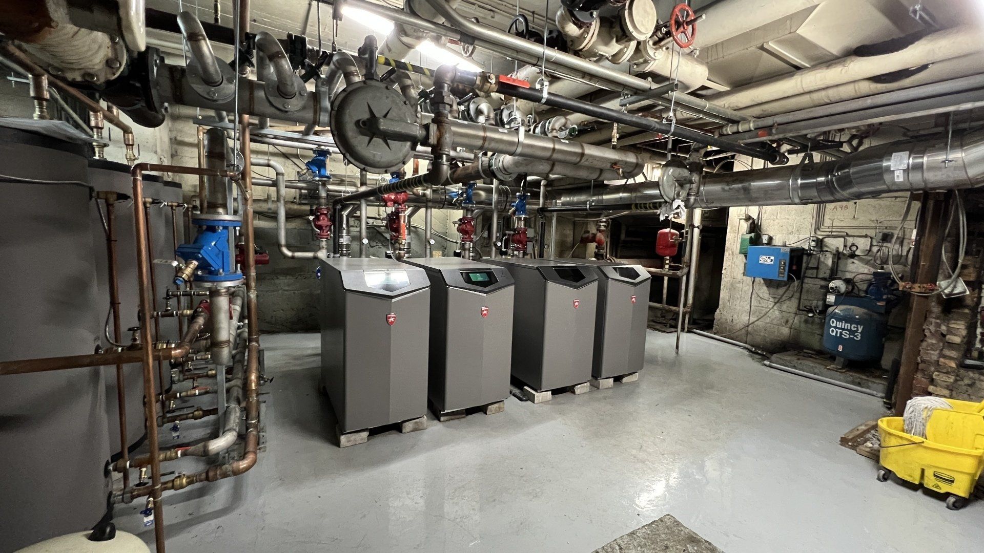 Une pièce avec beaucoup de tuyaux et une horloge au mur.